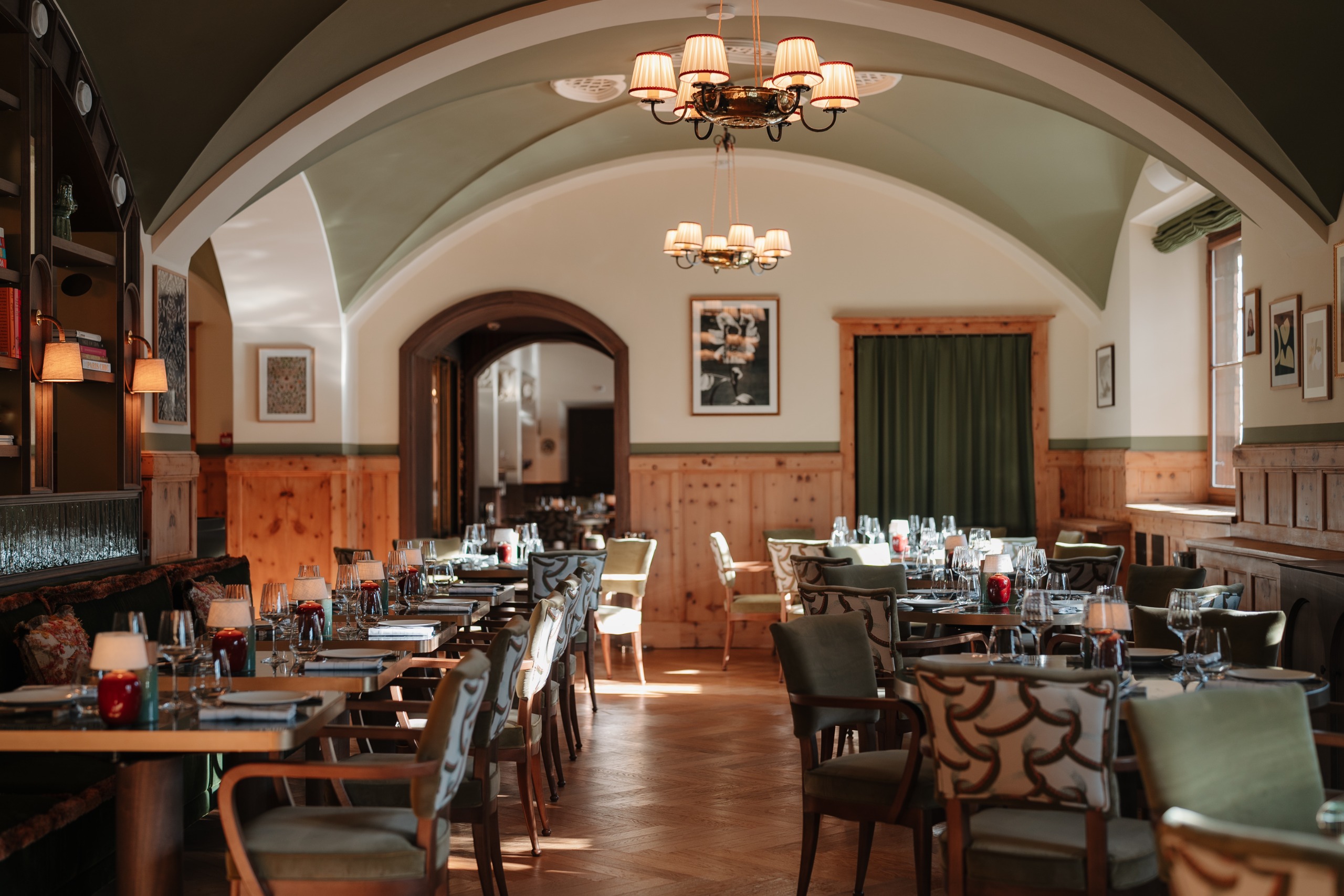 Hotel restaurant with an arched ceiling and wooden furniture upholstered in sage green
