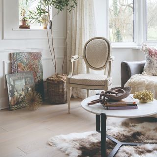 A living room with a round marble-effect top coffee table with curated items and a stack of books on top of an animal hide-style rug