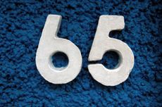 Raised number 65 house address on a building exterior.