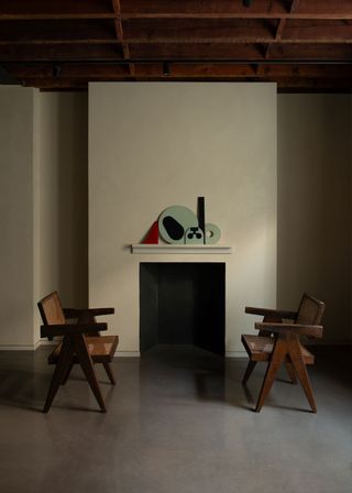 Ceramic art on mantel with two chairs by Pierre Jeanneret