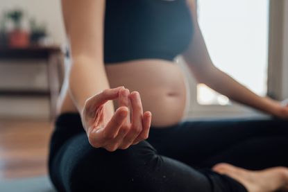 A close-up of a pregnant women practising pregnancy yoga online