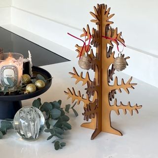 Un árbol de Navidad alternativo decorado con pequeños adornos navideños envueltos en cordel.