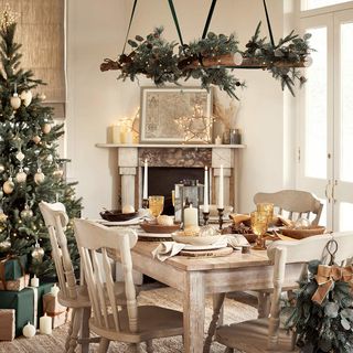 White dining room with wreath above table and Christmas tree
