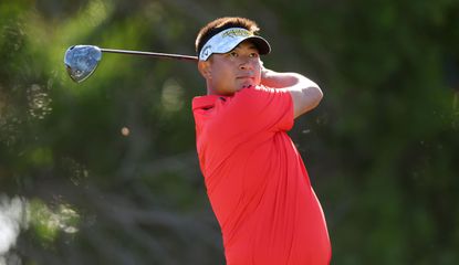 Carl Yuan watches his tee shot whilst wearing a red shirt