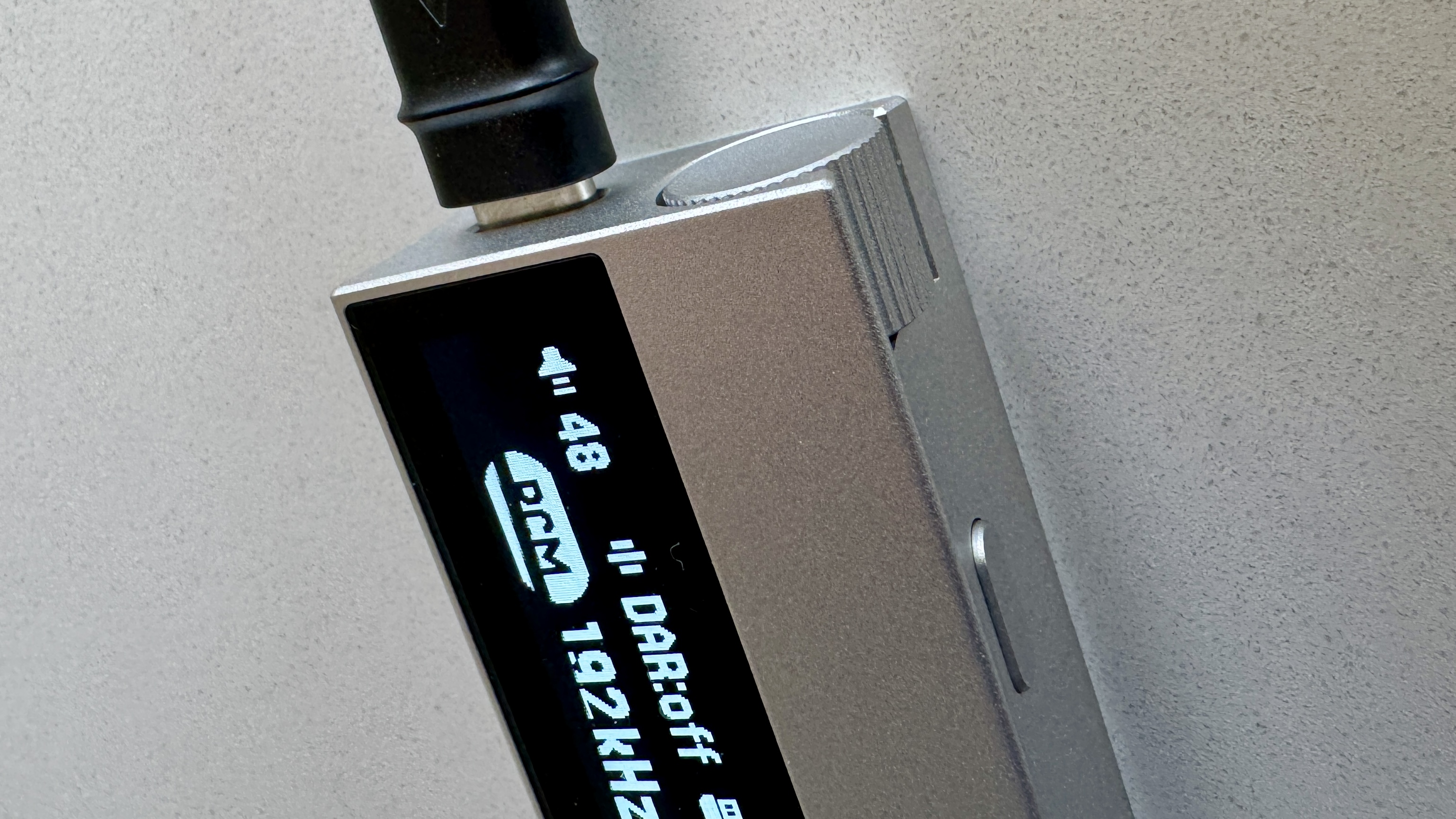 The Astell & Kern AK HC5 on a grey table, with the top plate illuminated and hooked up to Sennheiser IEMs and a FiiO digital audio player