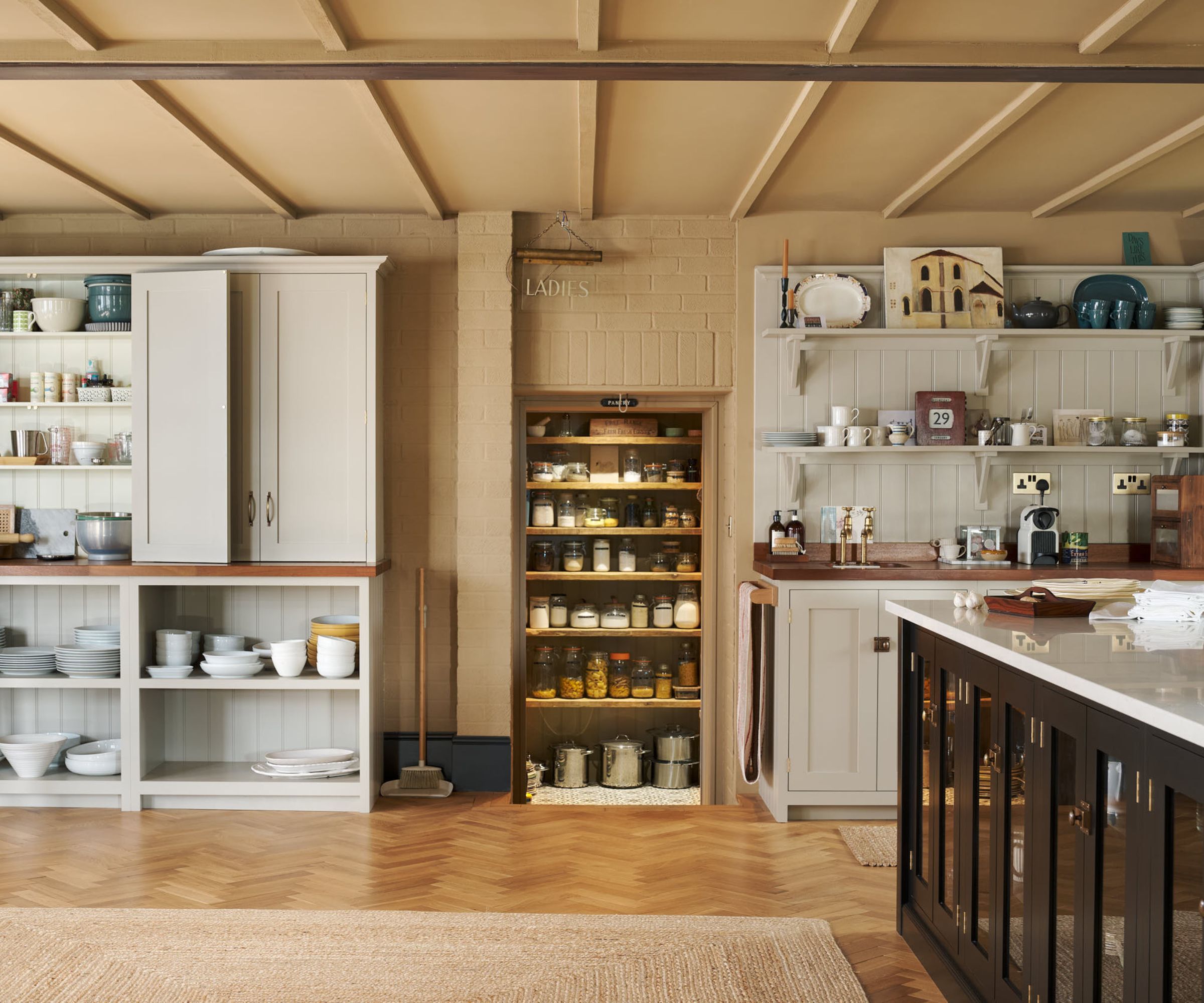 A large kitchen with gray cabinets and a niche transformed into a pantry