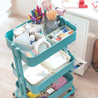 Workroom, converted home office in a house, with storage for craft materials and personalised stationery. A turquoise tiered trolley of craft materials.