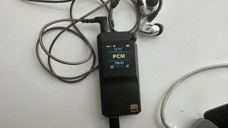 FiiO's BTR17 DAC/amp in black, on a gray table, showing PCM resolution in yellow font