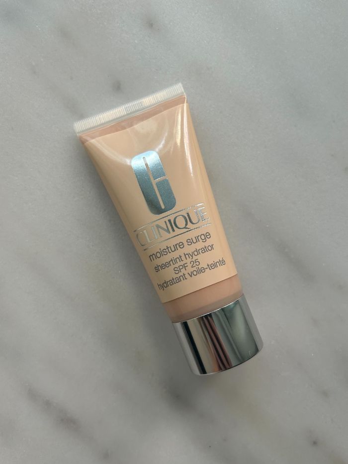The Clinique Moisture Surge Sheertint Hydrator SPF 25 on a marble table