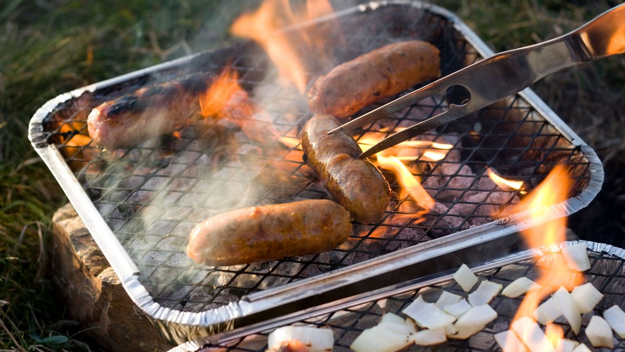 sausages cooking on a disposable BBQ