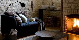 rustic living room with open fire and exposed stone walls