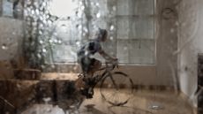 A cyclist rides indoors viewed through a rain soaked window