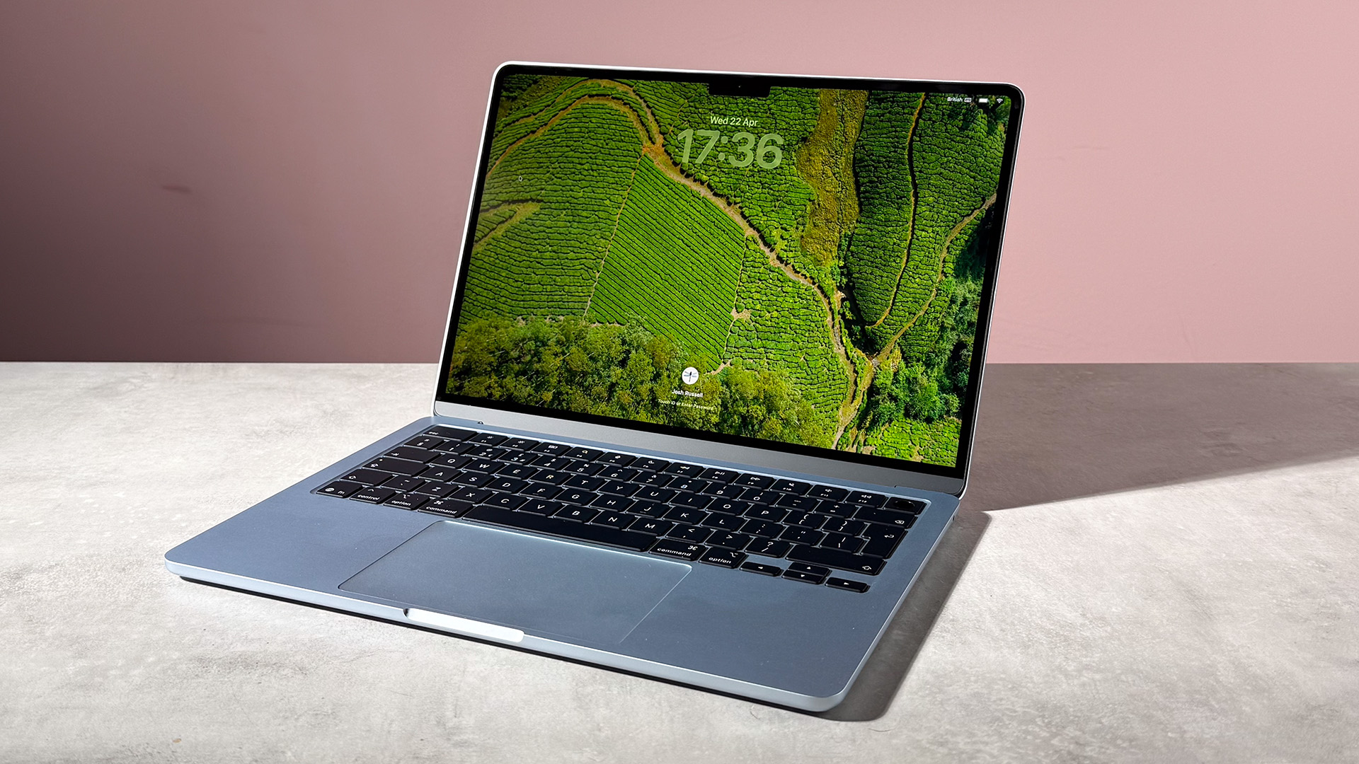 The MacBook Air M5 sky blue showing the lockscreen featuring rice fields from above.