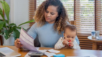Woman with baby on her lap looking at bills