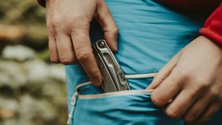 Close up of a hiker putting their camera in their trouser pocket