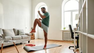 Man performing knee kick exercise at home