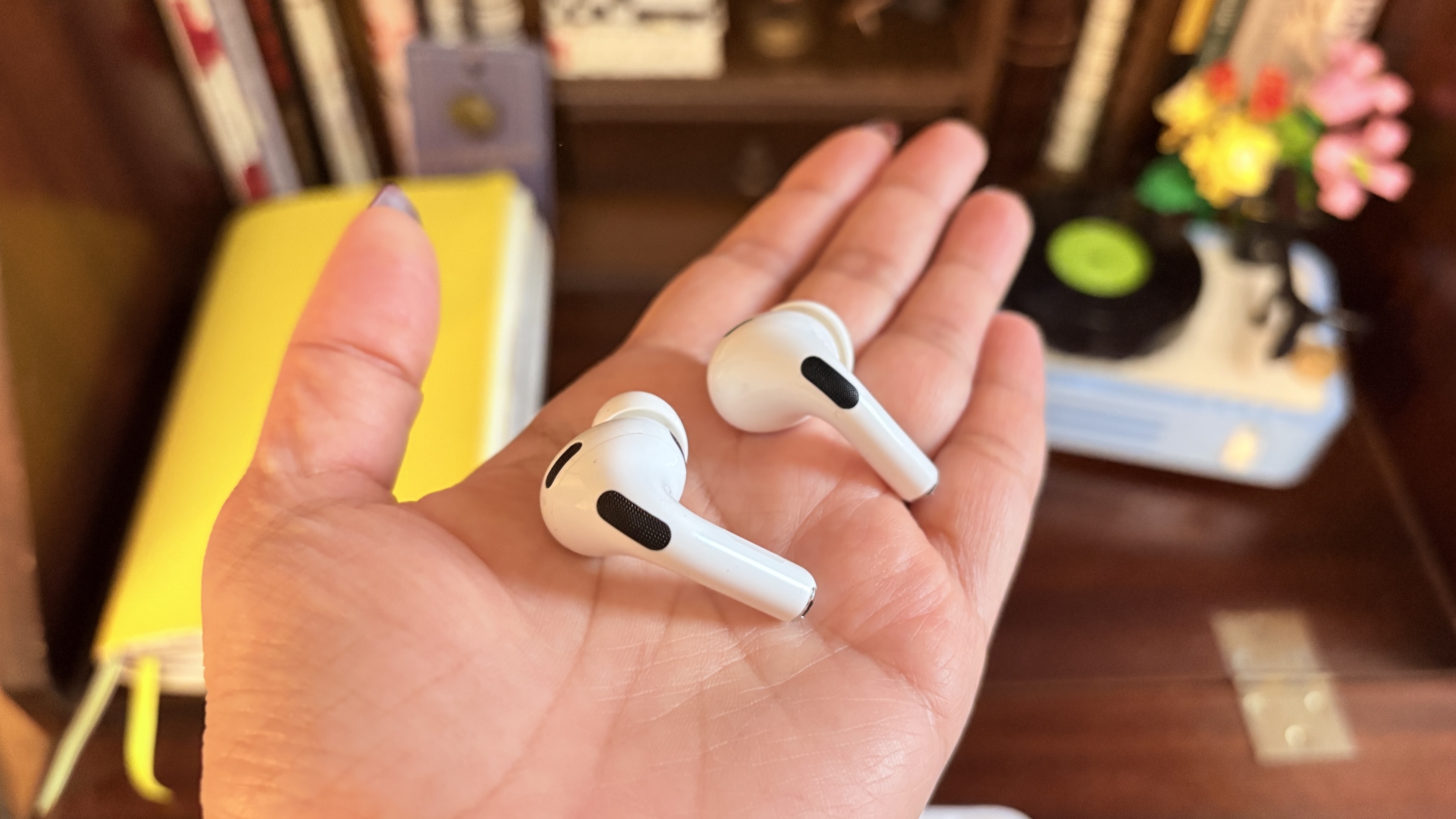 Apple AirPods Pro 3 and Pro 2 earbuds held in the palm of a hand.