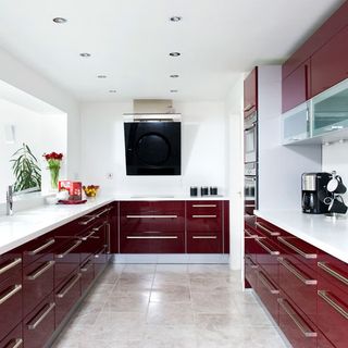 kitchen area with limenstone floor tiles and white wall and red cabinets