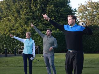 Three golfers shouting fore and point to the right after a wayward tee shot on the golf course