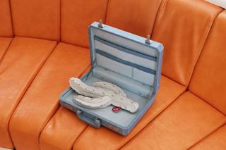 model cactus in open suitcase on orange sofa