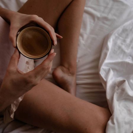 A woman drinking a cup of tea in bed