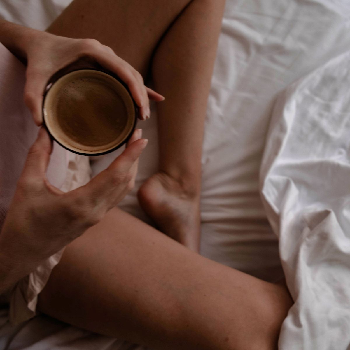 A woman drinking a cup of tea in bed