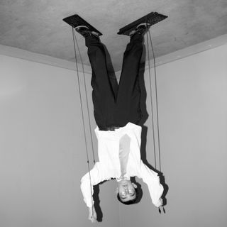 An upside down, black and white photo of a man standing on the ground wearing a suit. The photo makes it seem as though the man is standing on the ceiling