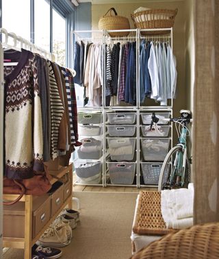 walk in closet area with open plan storage, hanging space, plastic boxes for knitwear, baskets, rug, bike