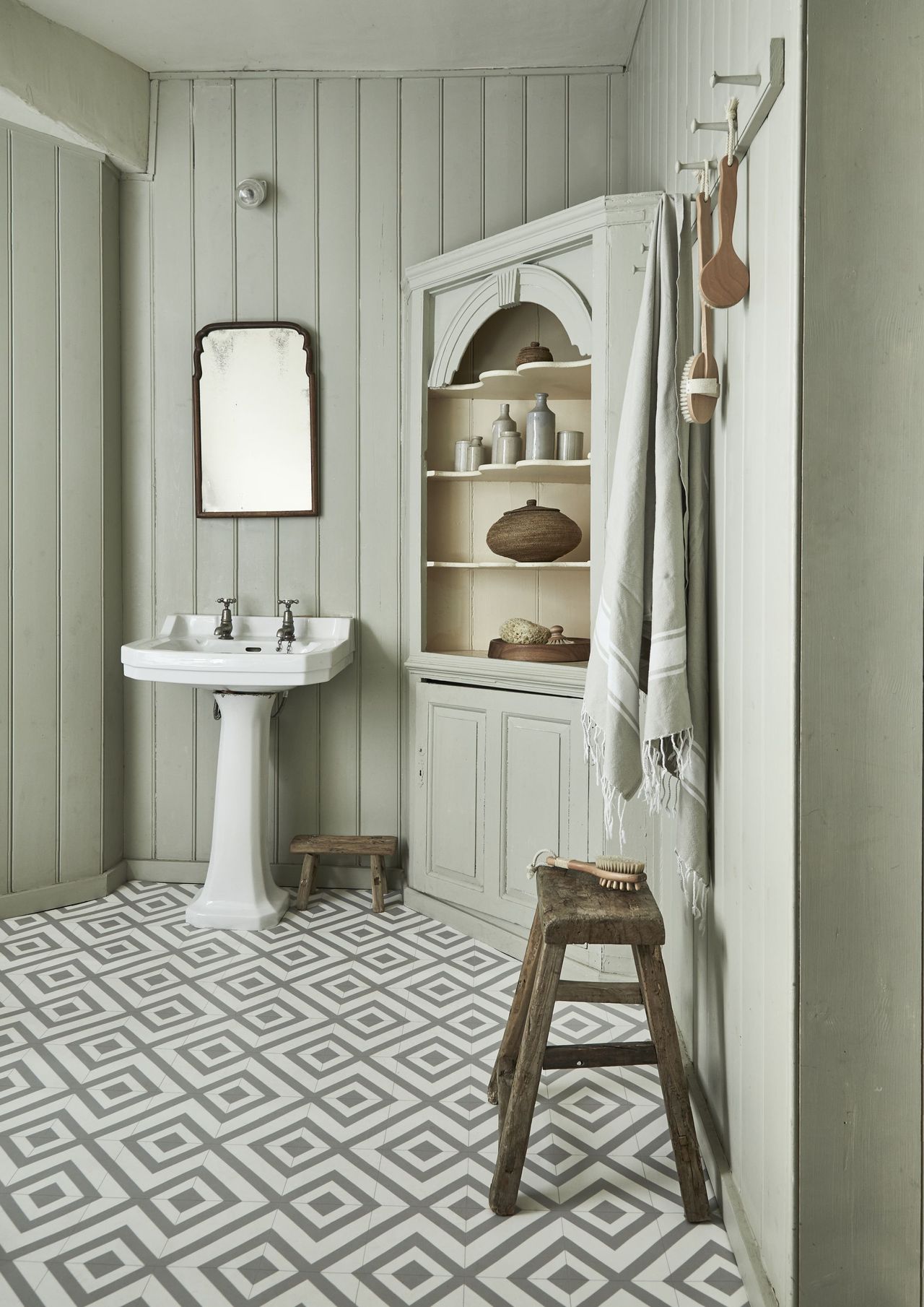 Cottage style bathroom with green painted wood walls, gray tiled floor, wooden bench and corner unit