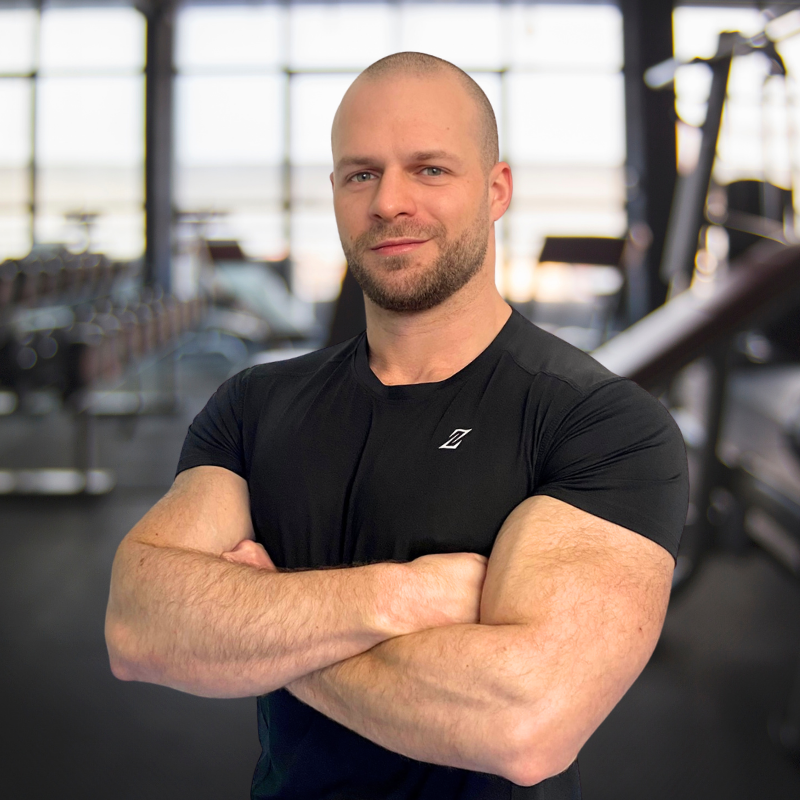 male personal trainer poses with arms crossed in gym