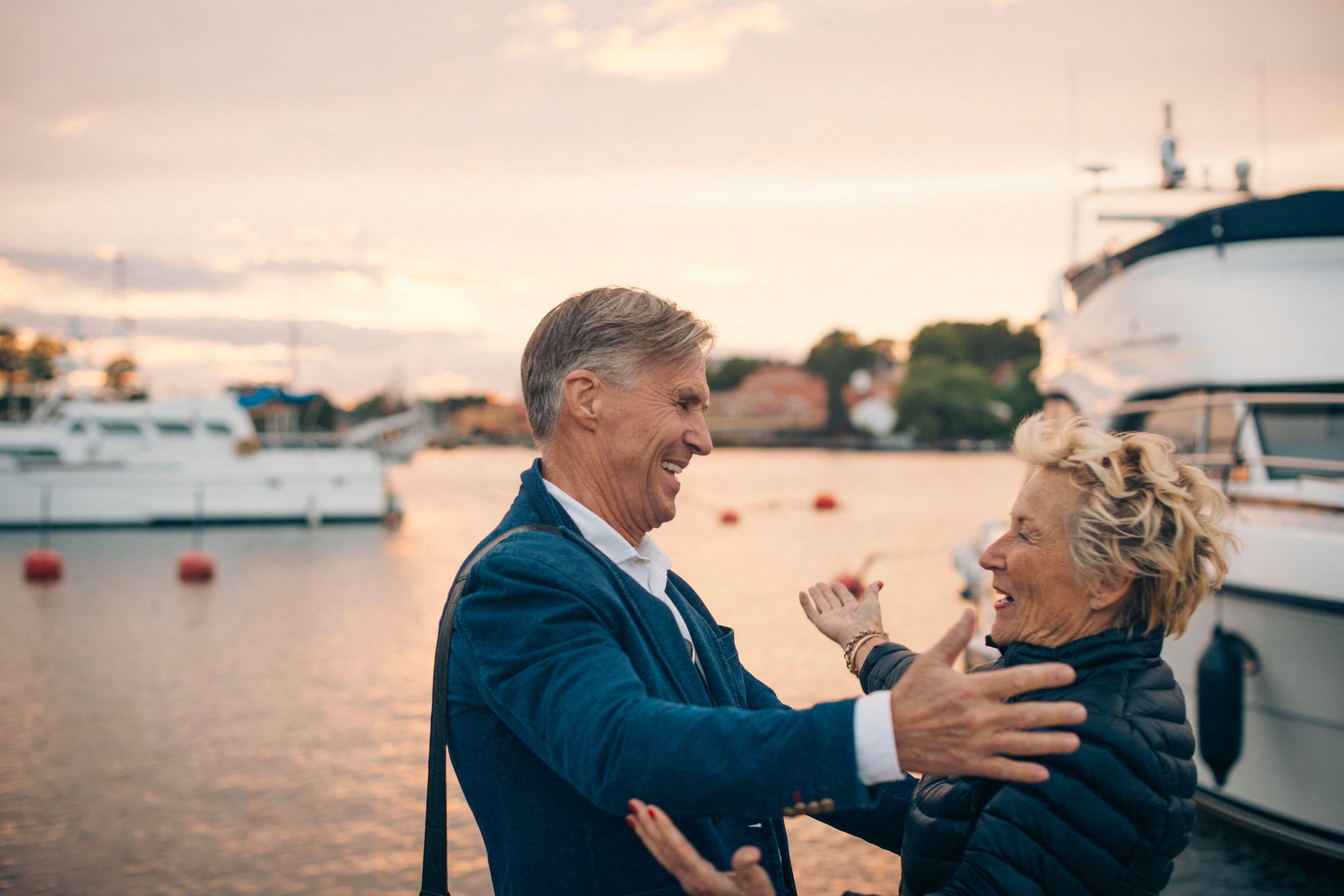 Side view of excited senior woman embracing man at harbor