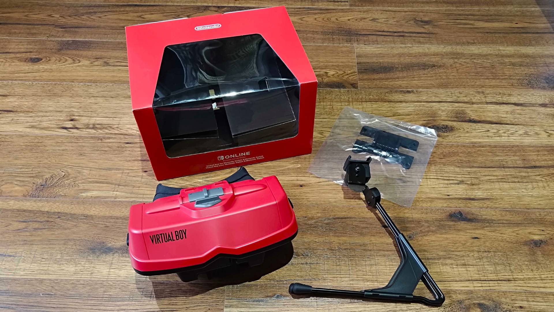 Virtual Boy for Switch 2 on floor next to box, stand, and adapter for original Switch.