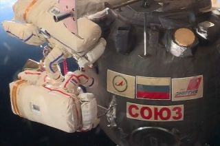 Russian cosmonauts Oleg Kononenko (in the spacesuit with red stripes) and Sergey Prokopyev (with blue stripes), both Expedition 57 flight engineers, cut into the exterior insulation of the Soyuz MS-09 spacecraft during a Dec. 11. 2018 spacewalk to expose the source of a pressurization leak, since patched, on board the International Space Station.