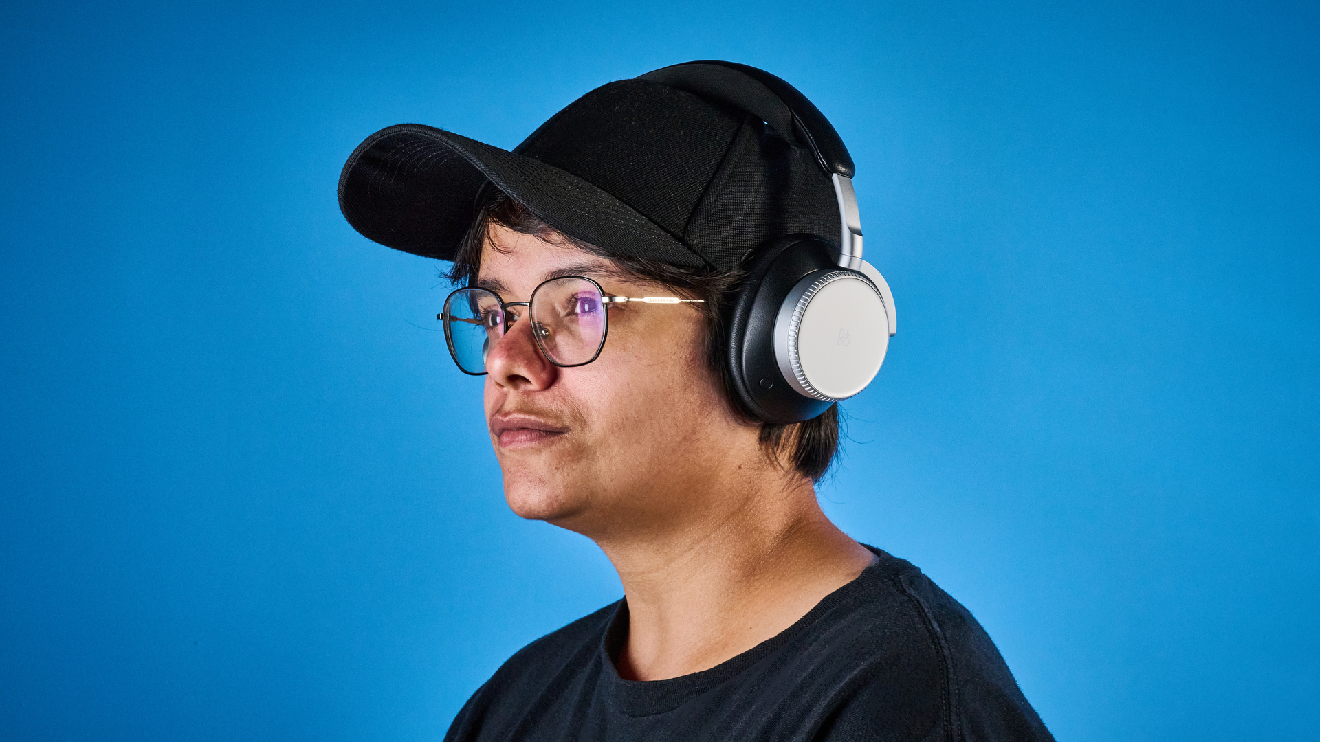 The Bang &amp;amp; Olufsen Beoplay H100 being worn on a person's head against a blue background
