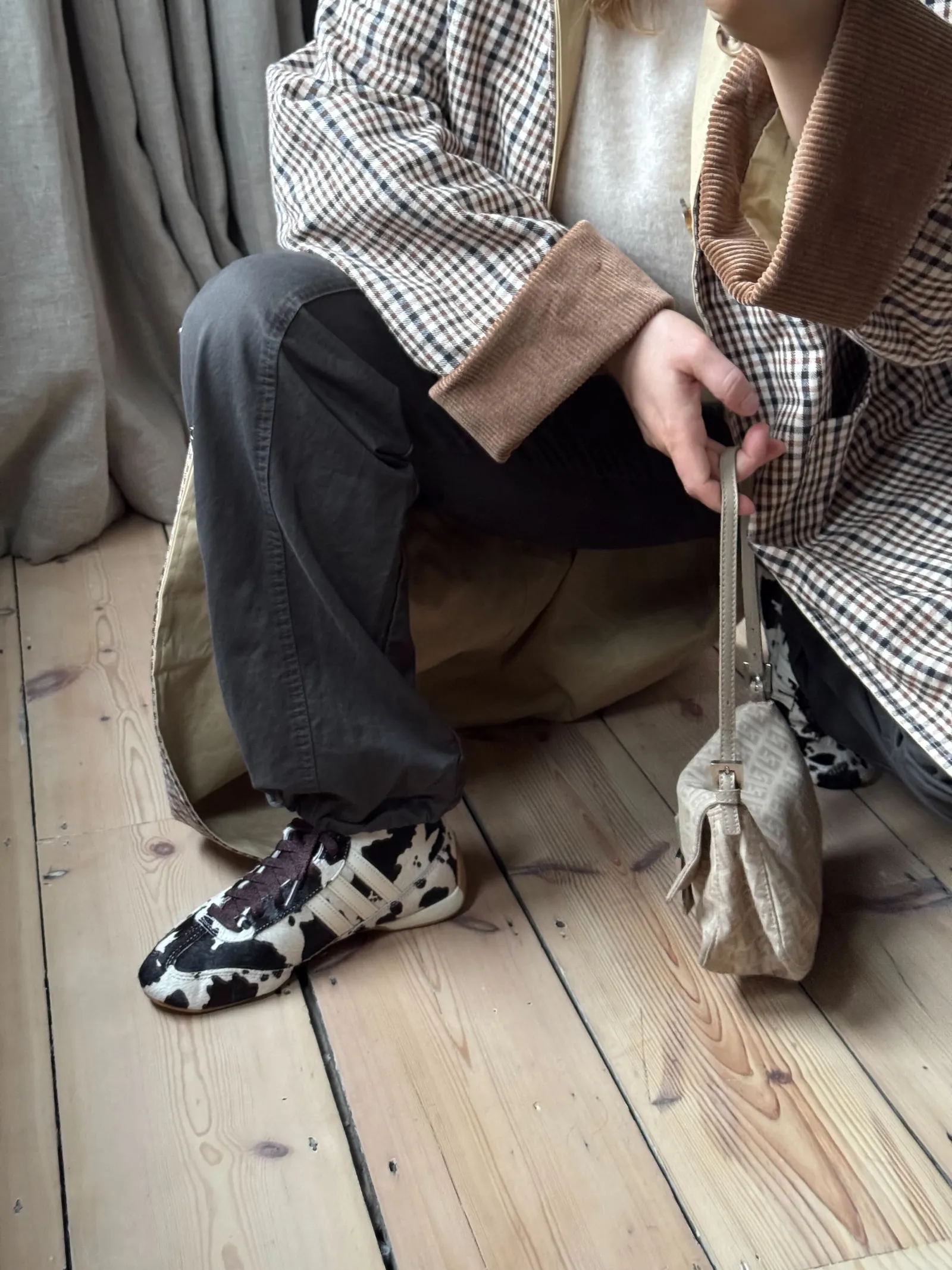 @rebeccarhysevans wears cow print trainers with black jeans and a checked jacket.