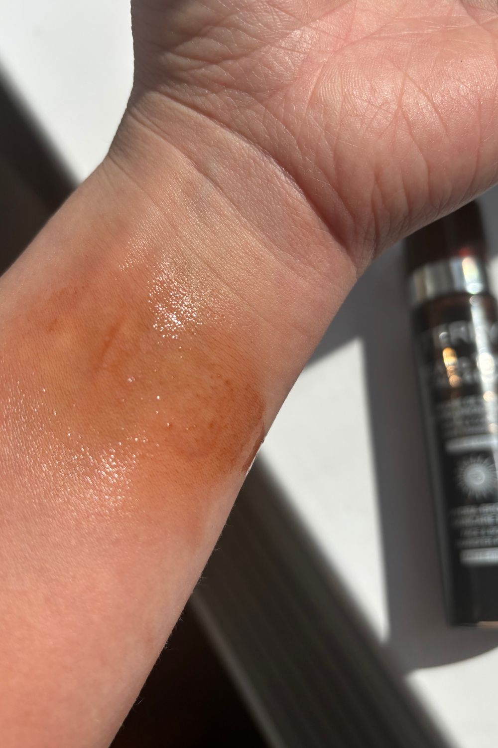 a wrist with a spritz of by terry tea to tan tanning water