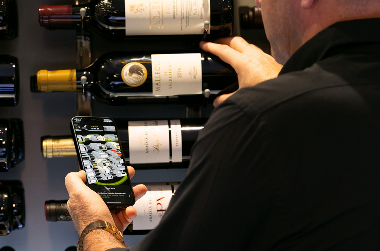man-selecting-bottle-from-wine-rack-using-app-visual-aid