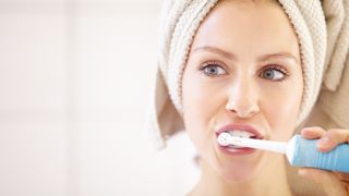 lady brushing her teeth with an electric toothbrush