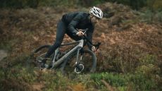 A man in a pair of the best winter bib tights riding a gravel bike through a wood 