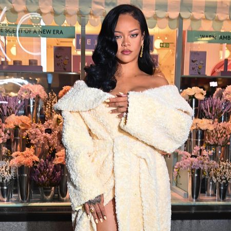 Rihanna wearing a curled side part hairstyle and a textured jacket as a dress.