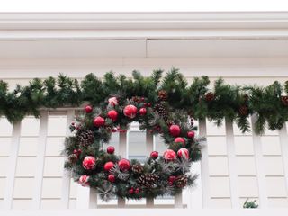 a wreath with red baubles and a garland on a white balcony