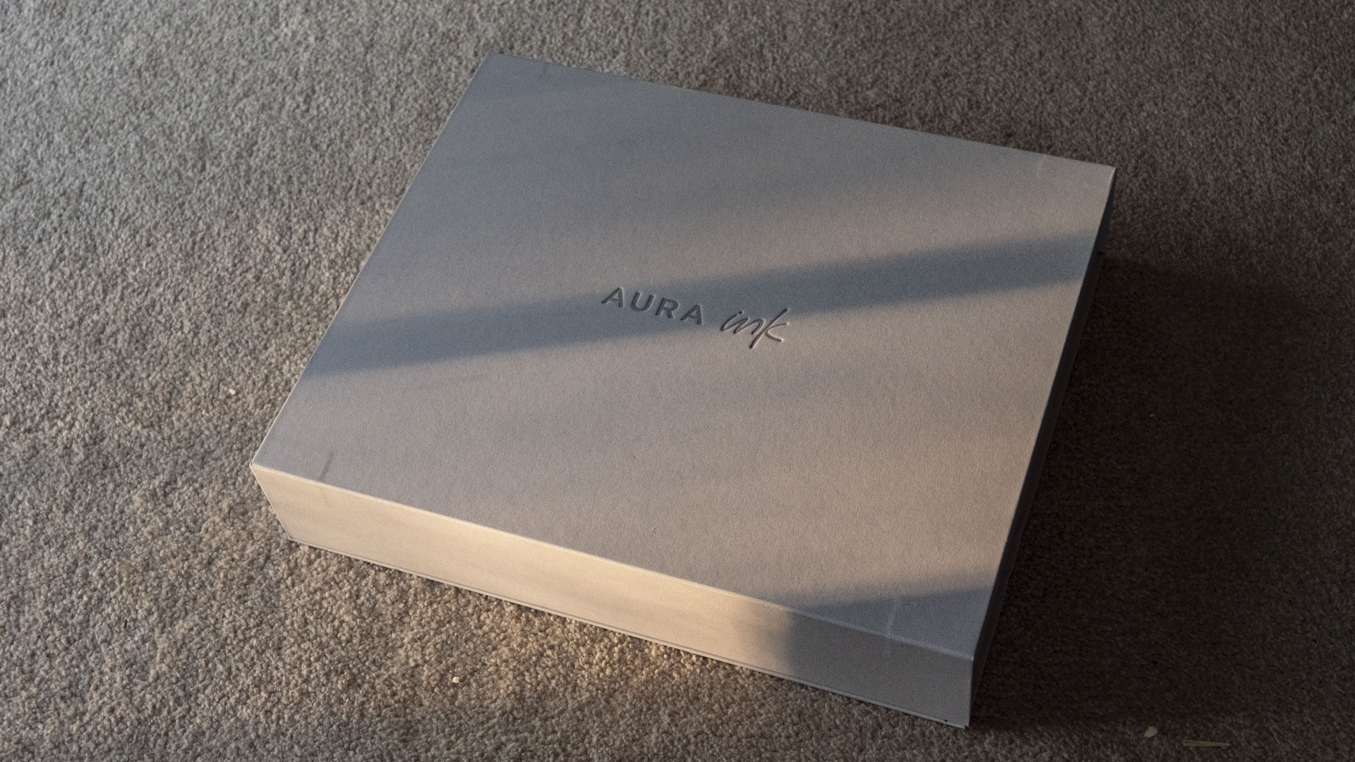 The Aura Ink 'E Ink' digital photo frame's presentation box, illuminated by the golden hour sun