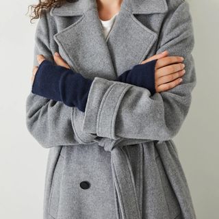 woman wearing navy fingerless gloves and a grey coat