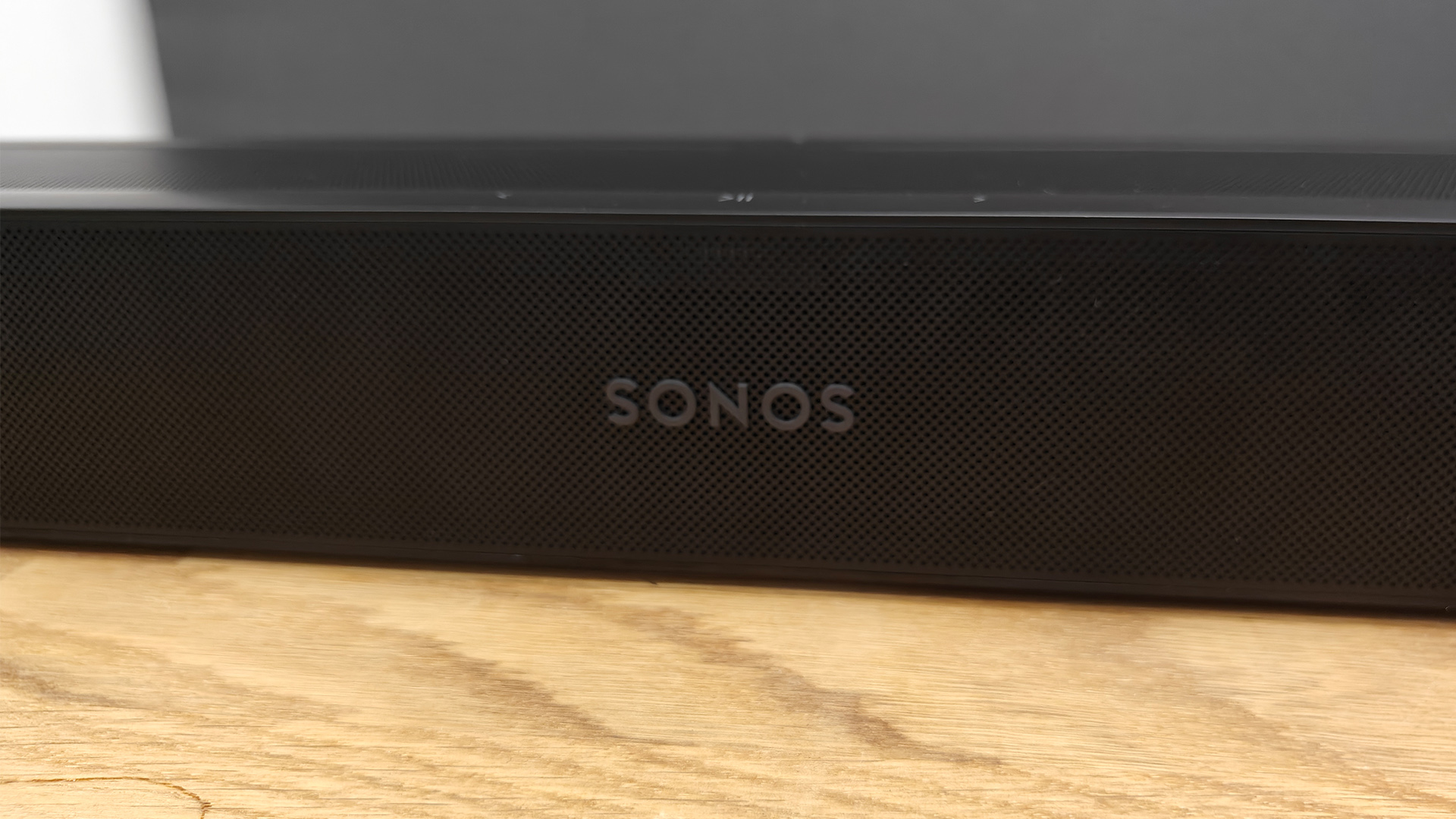 Sonos Beam Ultra Dolby Atmos soundbar on wooden AV unit detail of Sonos logo