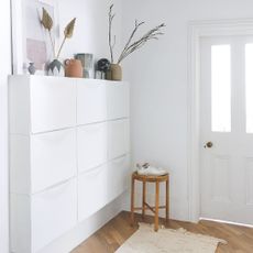 White painted hallway with white front door and white shoe storage fitted to the wall