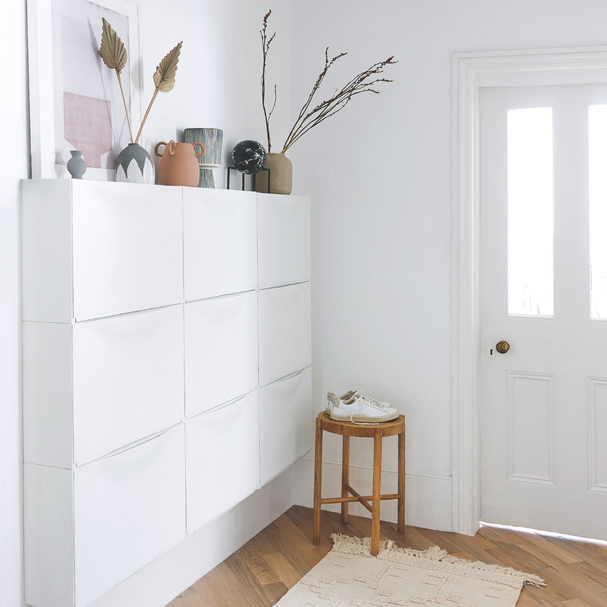 White painted hallway with white front door and white shoe storage fitted to the wall