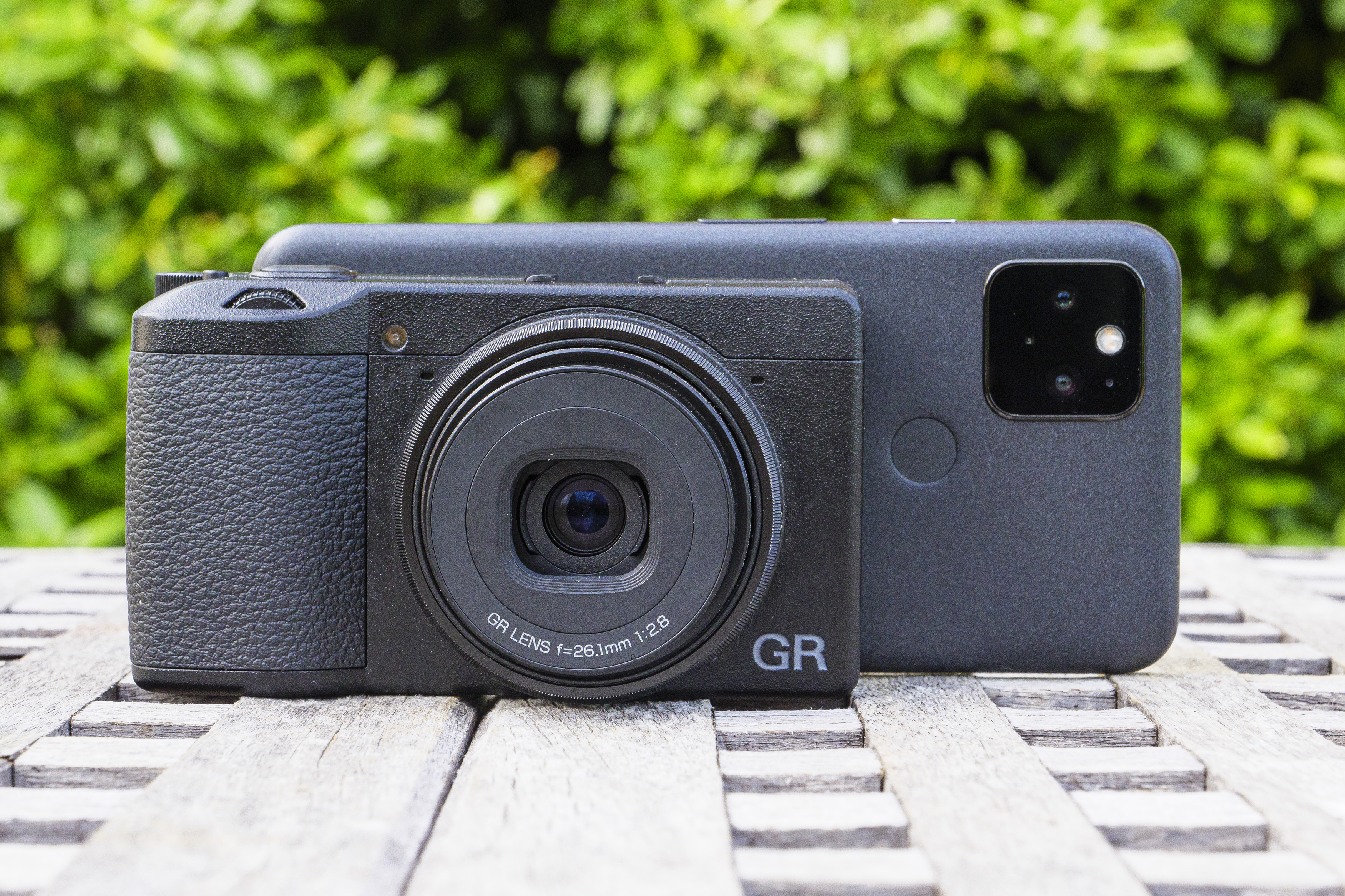 The Ricoh GR III X compact camera in front of a smartphone