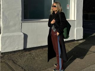 Fashion influencer @lucywilliams02 wearing an on-trend winter outfit in London with sporty burgundy Adidas pants.