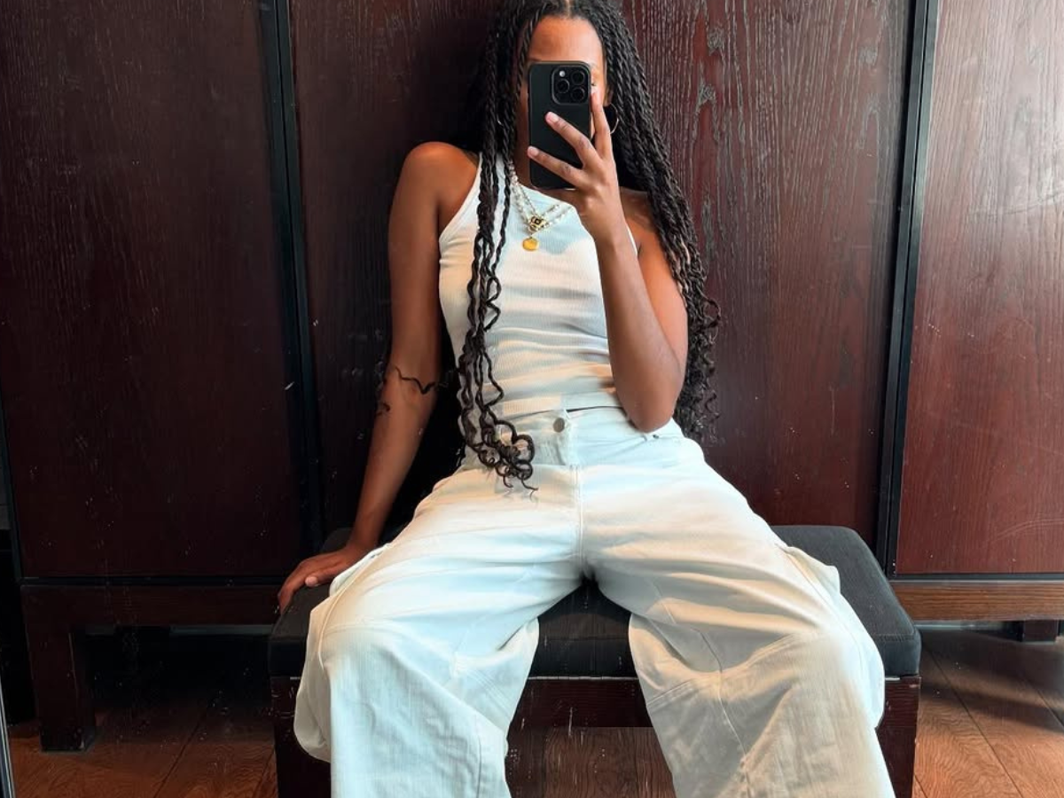 Woman wearing white tank and white wide jeans with sneakers in a summer 2025 outfit.