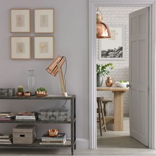 A light grey hallway with wall art, bronze lighting and a console table